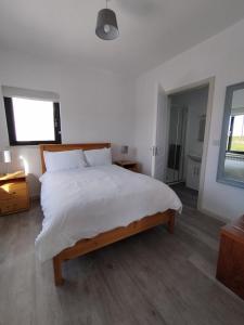 a bedroom with a large bed with white sheets at Craggy Cottage 1 in Inishturk +3 photos