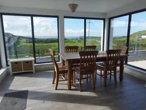 a dining room with a table and chairs and windows at Craggy Cottage 1 in Inishturk