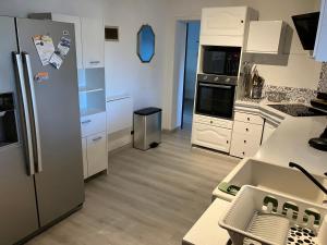 a kitchen with a stainless steel refrigerator and white cabinets at Maison familiale au cœur du bassin d'Arcachon in Biganos