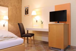 a hotel room with a bed and a desk with a television at Hotel Centro in Schwabach