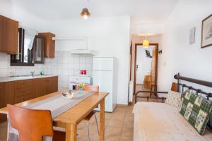 a kitchen with a wooden table and chairs in a room at Thalassia Studios in Kalamitsa