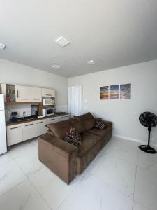 a living room with a brown couch and a kitchen at Seu Lar Temporário in Penha