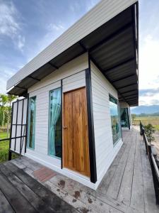 Una pequeña casa con una puerta de madera en una terraza. en นาน้าหมูฟาร์มสเตย์ NanamooFarmStay, en Trang 2 fotos más