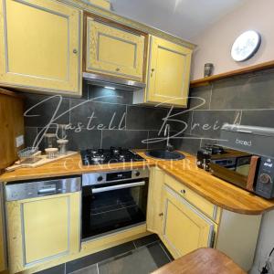 a kitchen with yellow cabinets and a stove top oven at Le Cocon du manoir de Kerollivier in Saint-Gilles-Pligeaux