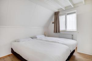 a white bed in a room with a window at Kuifeend I Chalet met Modern Interieur in Zwiggelte +41 photos