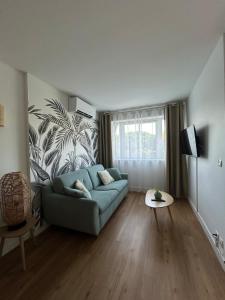 a living room with a blue couch and a wall at Appartement proche plage, CARNON in Mauguio