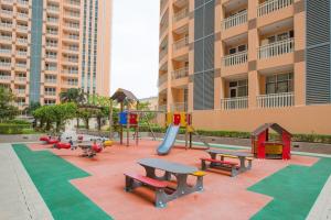 einen Spielplatz mit Bänken und einer Rutsche vor einem Gebäude in der Unterkunft Cozy Home at Venice Luxury BGC in Manila