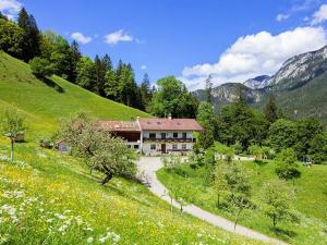 a house on a hill with a road in a field at Pension Scheuerbichl in Bischofswiesen