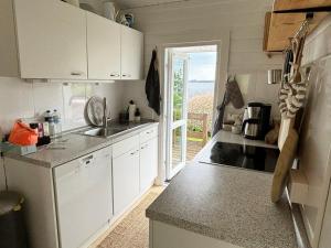 une cuisine avec des armoires blanches et une porte ouverte dans l'établissement Coast Seven, à Borgwedel