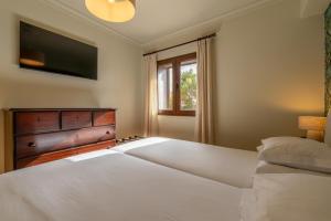 a bedroom with two white beds and a television at Hotel Quinta Do Furao in Santana