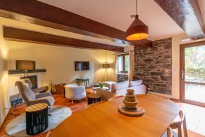 a living room with a wooden table and a stone wall at Hotel Quinta Do Furao in Santana