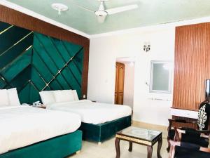 a hotel room with two beds and a green headboard at Hayat Grand Guest House in Islamabad