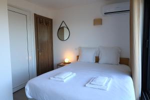 Un dormitorio con una cama blanca con dos toallas encima. en Superbe studio - Terrasse 360 avec vue mer, en Pianottoli-Caldarello 17 fotos más
