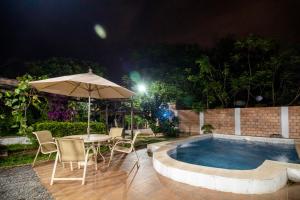 a table with chairs and an umbrella next to a pool at La Casita de Aregua in Itauguá