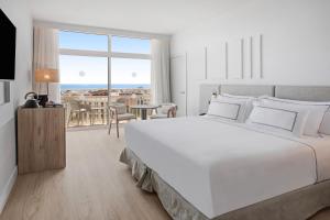 a white bedroom with a large white bed and a table at Meliá Lloret de Mar in Lloret de Mar