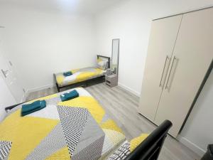 South NorwoodにあるNEW 5-bedroom house in Croydon South Londonのベッド2台、冷蔵庫が備わる小さな客室です。