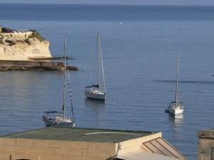 tres barcos sentados en el agua cerca de un muelle en Il-Guva Penthouse at Marsalforn, en Marsalforn