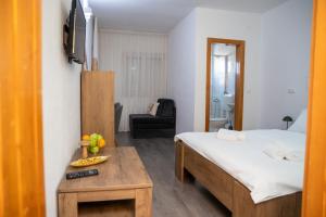 メジュゴリエにあるGuest House Rosanda, 200m from Churchのベッド、テーブル、テレビが備わるホテルルームです。