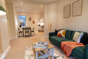 a living room with a green couch and a table at Stylish Gateway-2 bedroom house -5 minutes from the beach in Eastbourne