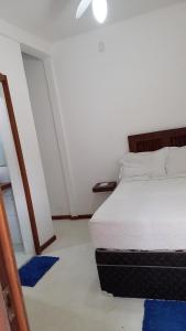 a bedroom with a white bed and blue rug at hospedagem da Mari in Jericoacoara
