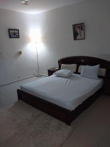 a bedroom with a large bed with white sheets and a lamp at Chez Ousmane Fall ASECNA apparemment F2 in Ngalel