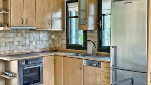 a kitchen with wooden cabinets and a stainless steel refrigerator at Granari Olive Nest in Diaporos