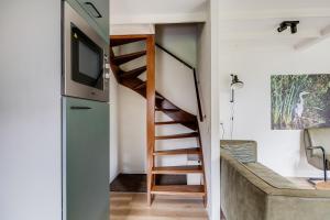 a spiral staircase in a tiny house with a tv at Blauwreiger I Geniet in dit Moderne Huisje in Zwiggelte