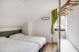 two beds in a small room with a window at Blauwreiger I Geniet in dit Moderne Huisje in Zwiggelte