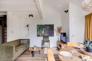 a living room with a couch and a table at Blauwreiger I Geniet in dit Moderne Huisje in Zwiggelte