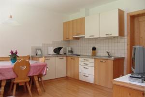 una cucina con tavolo e una cucina con armadietti bianchi di Oberlindnerhof a San Lorenzo di Sebato Altre 30 foto