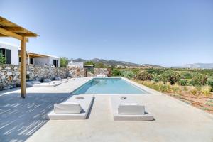 ein Schwimmbad mit Liegestühlen und ein Haus in der Unterkunft Stone Pine House Antiparos - Private Pool Villa in Andiparos