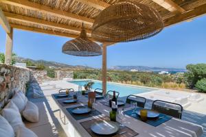 eine Terrasse mit Tisch und Stühlen und ein Swimmingpool in der Unterkunft Stone Pine House Antiparos - Private Pool Villa in Andiparos
