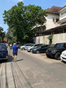 Un homme marchant dans une rue avec des voitures garées dans l'établissement CorriDoor Daily Homestay, à Bandung 4 autres photos