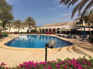 una piscina en un complejo con flores rosas en charmante villa en résidence en bord de mer, en Saly Portudal