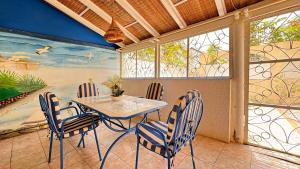 un comedor con mesa, sillas y un mural en charmante villa en résidence en bord de mer, en Saly Portudal