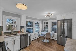 a kitchen with white cabinets and a table with chairs at Sea Glass Cottage-in the heart of Clinton Harbor! in Clinton