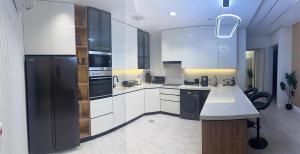 a kitchen with white cabinets and a black refrigerator at Riyadh luxury family Apartment AlYasmin in Riyadh