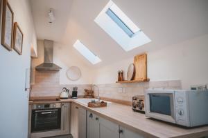 Il comprend une cuisine avec un comptoir, un four micro-ondes et une télévision. dans l'établissement Nurse's Cottage, Tissington, Derbyshire, à Ashbourne