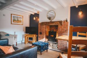 Il comprend un salon doté d'une cheminée en briques et d'une télévision. dans l'établissement Nurse's Cottage, Tissington, Derbyshire, à Ashbourne