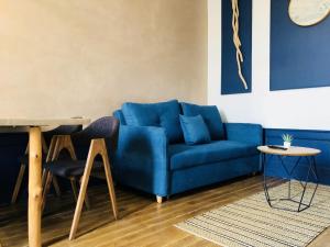 a blue couch in a living room with a table and chairs at Meublés de l'Arsenal cœur de ville ! in Angoulême +24 photos