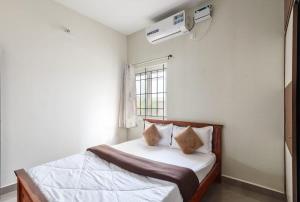a bedroom with a bed with white sheets and a window at Blue Nest By StayJadeParty VillaLawn in Hosūr