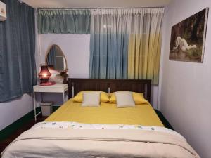 een slaapkamer met een geel bed en een spiegel bij Kanlayana Hostel in Ban Bang Toei (1)
