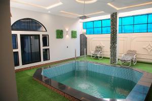 a swimming pool in a house with two chairs at Grand Shalimar Hotel in Multan