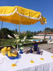 a table with a yellow umbrella and some food on it at Casa da Carlota in São Vicente de Pereira Jusã
