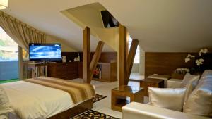 ein Schlafzimmer mit einem Bett, einem Fernseher und einer Couch in der Unterkunft Hotel Xperience in Jounieh