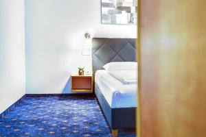 a bedroom with a bed with a blue carpet at Smarthotel Schmid - Restaurant & Bar inhouse - Nähe Schlossteich in Sitzenberg +44 photos