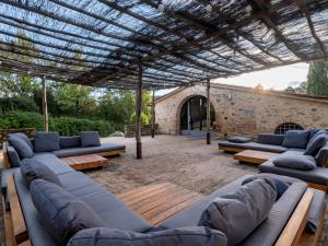 a patio with blue couches and tables and a stone building at Villa Poggio alla Staffa in Poderi Foci