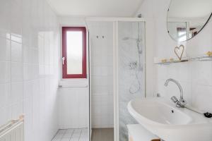 a white bathroom with a sink and a shower at Nachtzwaluw I Huisje met Buiten Zitplek in Zwiggelte