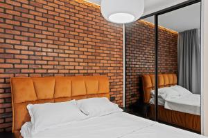 a bedroom with a brick wall and a bed and a mirror at VILLA THERME - Luxurious Villa near Therme SPA & Airport in Corbeanca