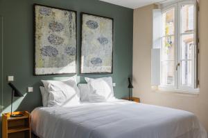 a bedroom with a white bed with two pictures on the wall at Campagne Mirasol in Uchacq-et-Parentis +29 photos